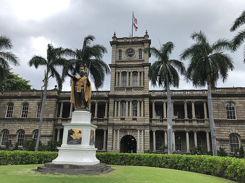 Photo of Hawaii's Supreme Court building on a cloudy day, with King Kamehameha statue out front. 