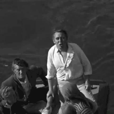 Charles Laughton in white naval blouse and trousers, shouts and raises his fist from the tiller of an open boat in 1935 film Mutiny on the Bounty - animated gif