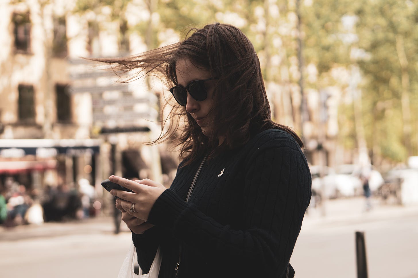 woman texting on street with city background