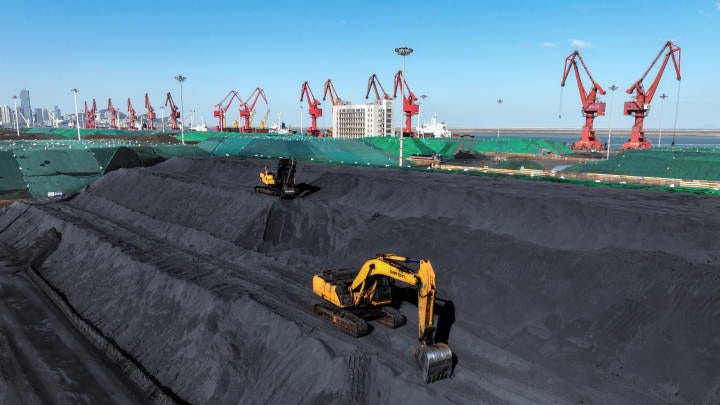 Excavators transfer coal at the coal terminal in China's eastern Jiangsu province on January 22, 2024.