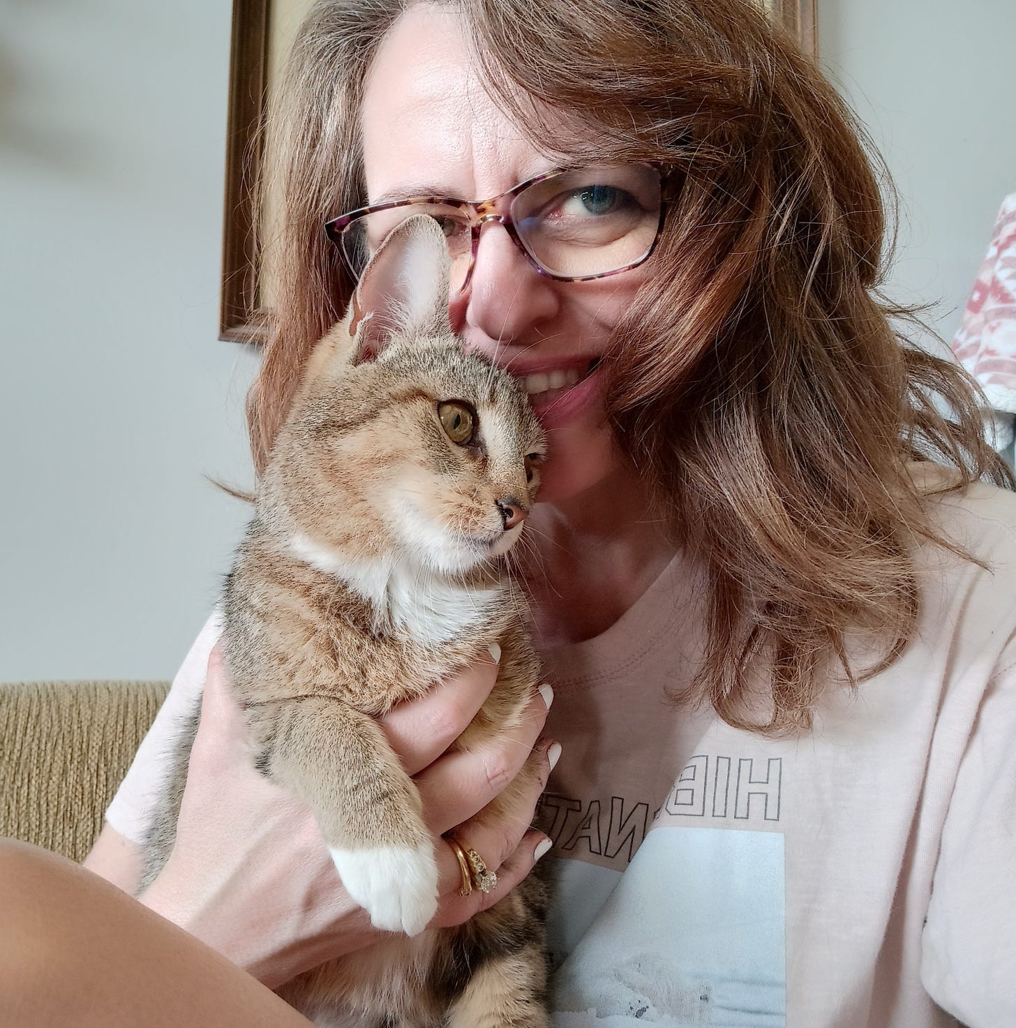 woman with glasses holding small cat