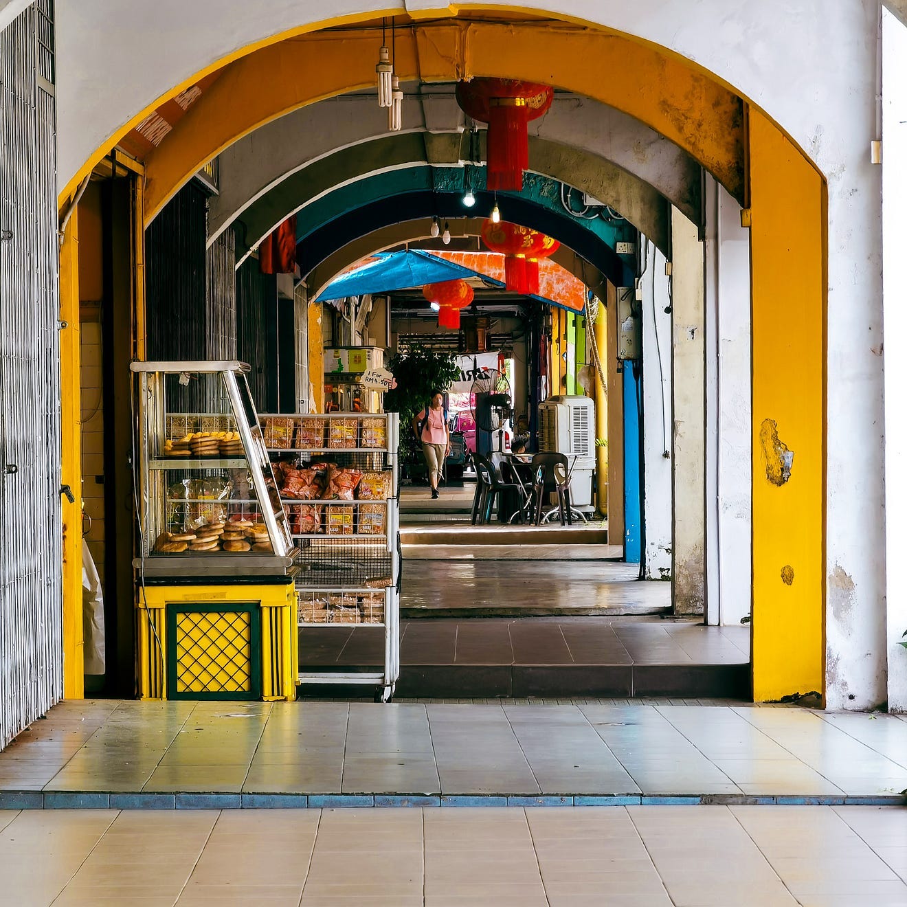 picture of many archways in a malaysian street, people in the distance