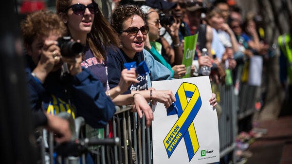   Fans with a "Boston Strong" poster cheer on runners as they finish the Boston Marathon in April 2014.