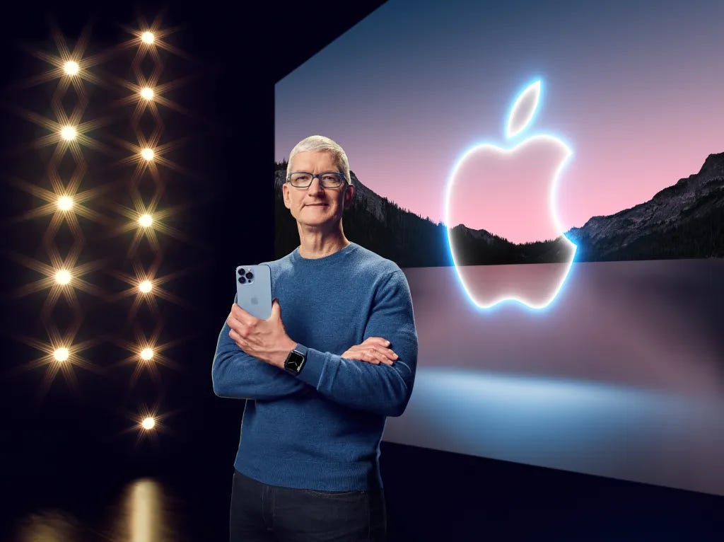 CEO Tim Cook posing for a photo while holding a blue iPhone.