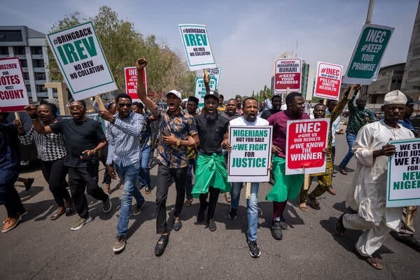 Demonstrators holdings signs of green, red, white and black marching on a Nigerian street.