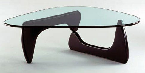 It’s a modernist table made a’ two identical pieces a’ curved wood with a heavy plate glass top. Very chic!