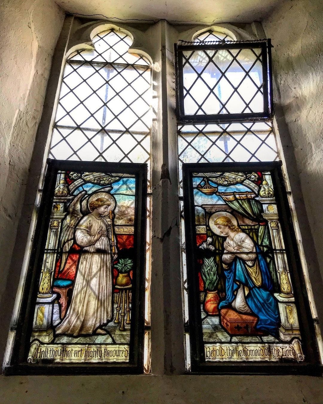 A photo inside the tiny Binsey church by Sarah Rhodes of the stained glass windows above the font at the western end.