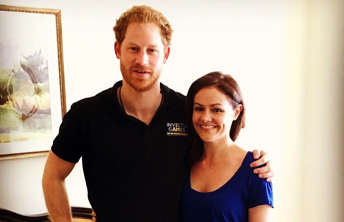 Prince Harry wearing dark Invictus Games polo shirt with arm round Emily Nash