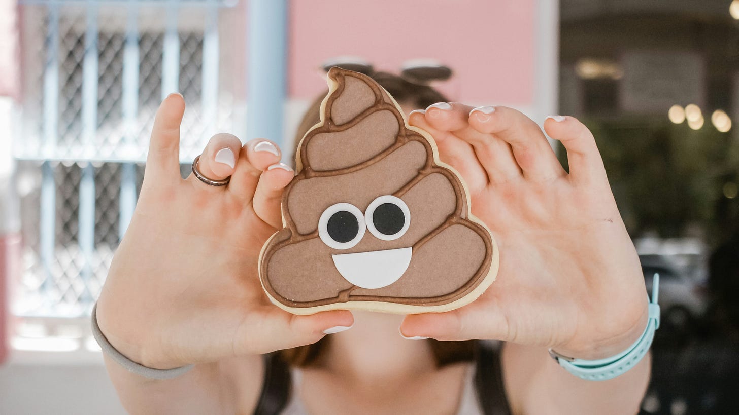 A person holding a poop emoji cookie