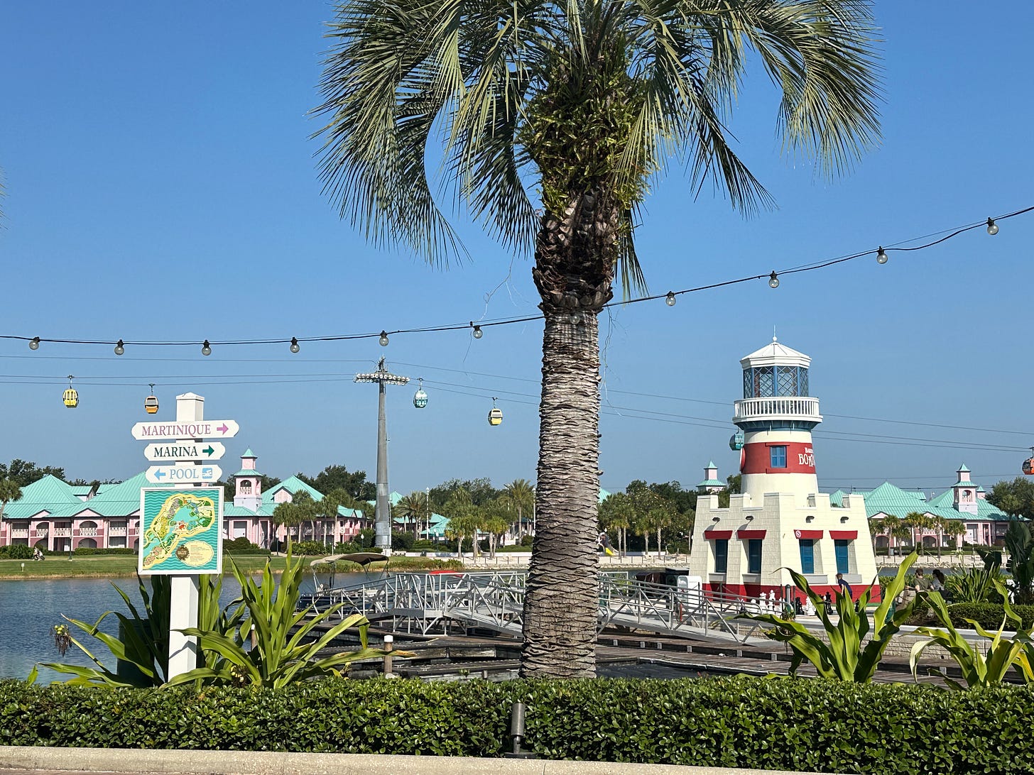 Palm tree, faux lighthouse, hanging lights, sign pointing way to different areas of Caribbean Beach Resort