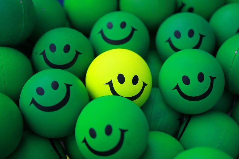 Smiles on various green bouncy balls and one is almost yellow in color.
