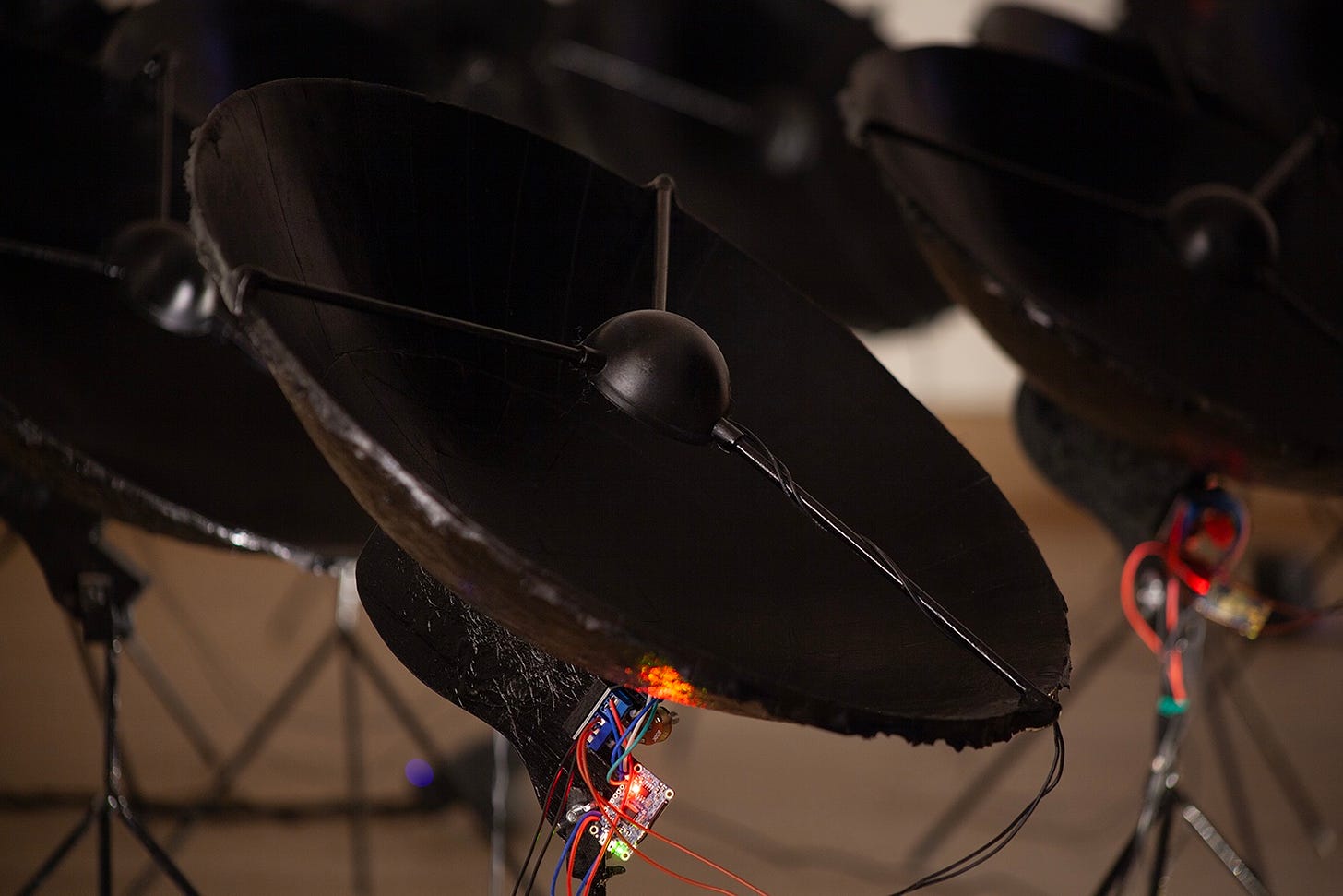 Close up view of one speaker. The speaker is shaped like a satellite dish and is painted black. beneath it the electronic components that make up the speaker and mp3 player are visible.
