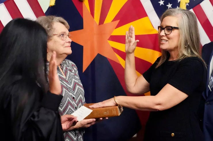 The new Arizona Democratic Gov. Katie Hobbs, right, takes the oath of office in a ceremony as U.S. Circuit Judge for the Ninth Circuit Court of Appeals Roopali Desai, left, administers the oath while Hobbs' mother Linda holds the Bible at the state Capitol in Phoenix, Monday, Jan. 2, 2023. 