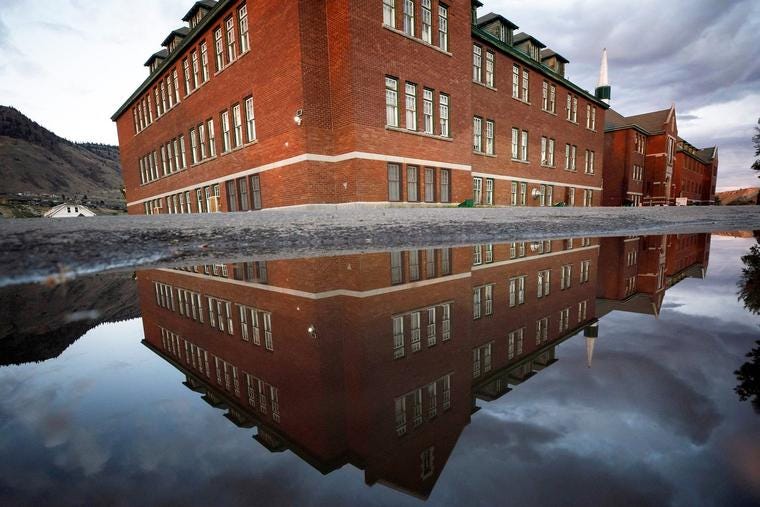 The former Kamloops Indian Residential School is reflected in a pool of water in Kamloops, Canada, on Sept. 1, 2021.