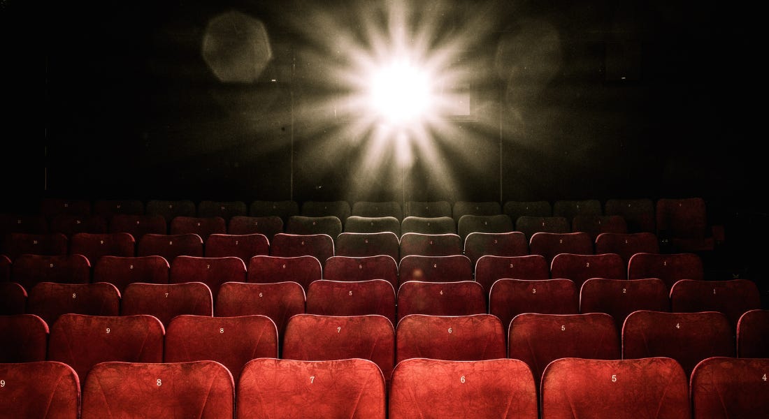 A row of red velvet cinema seats with a spotlight in the background