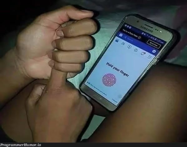 Na obrazovce telefonu svítí nápis „Přidržte svůj prst“ a uživatel drží ukazováček pravé ruky v hrsti levé ruky.