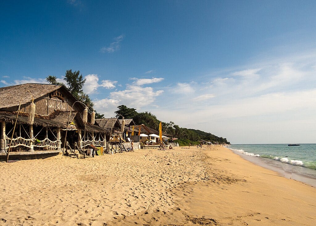 Beach shacks on a golden sandy shoreline in Ko Lanta, Thailand.