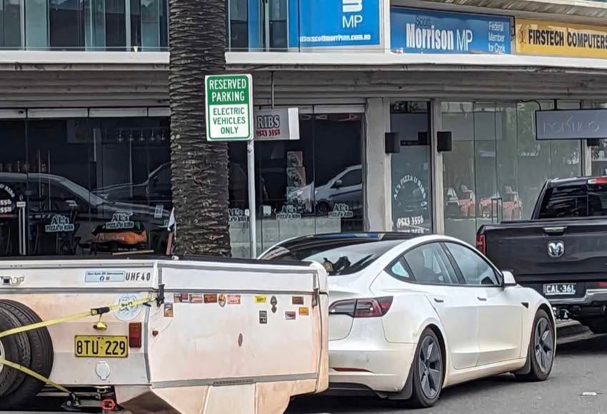Photo of Tesla hooked up with a caravan parked along the street outside Scott Morrison MP's Office