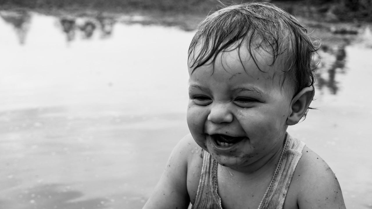 Little boy splashes in puddles