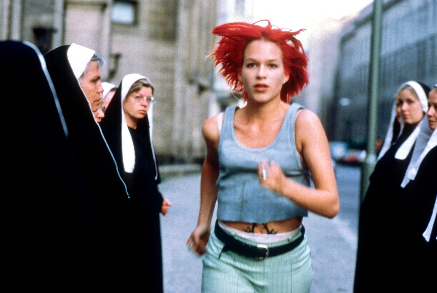 A young woman with red hair runs between a group of nuns