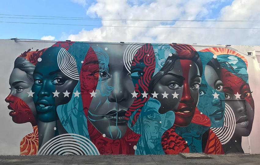 A street art mural of women's faces in colors of red, blue, white and shades of gray