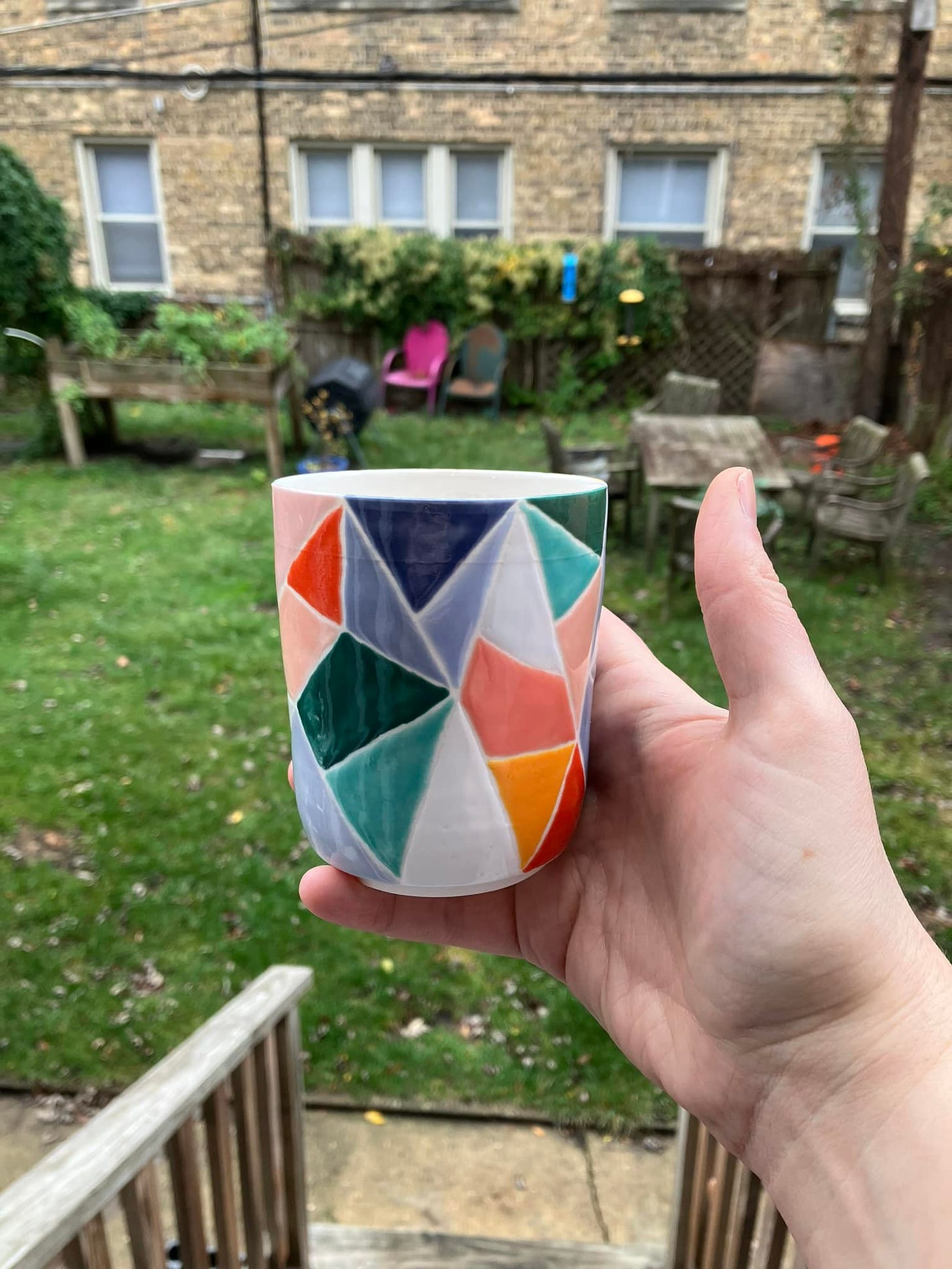 multicolored porcelain cup in the outdoors, with grass and apartment building behind