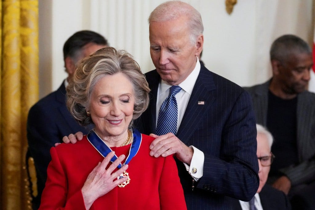 U.S. President Joe Biden awarding the Presidential Medal of Freedom to former Secretary of State Hillary Clinton in the East Room of the White House