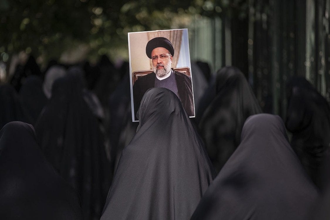 Iranian women wearing black hijabs hold up a photo of President Ebrahim Raisi during a pro-government protest in Tehran.