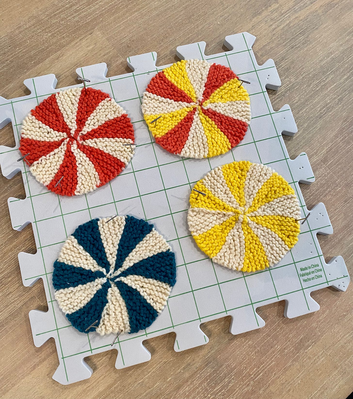 4 hand knit drink coasters on a knitting blocking mat