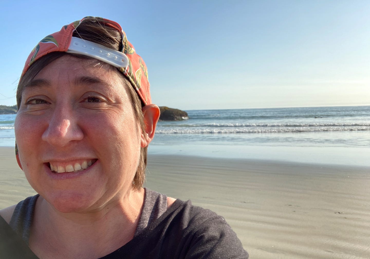 me, a white, sunburned person wearing a backwards hat with a bright print, grinning like a fool on a beach in tofino. 