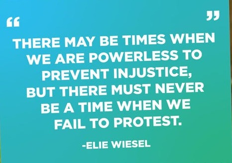 May include: A teal-colored yard sign with a quote by Elie Wiesel. The quote reads: 'There may be times when we are powerless to prevent injustice, but there must never be a time when we fail to protest.' The sign is displayed on a grassy lawn.
