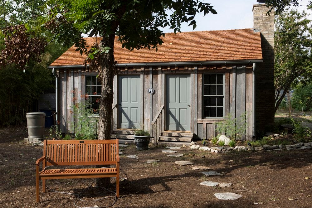 House with two blue doors and a wooden brown bench in front of it