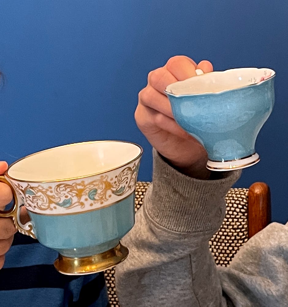 two robins-egg-blue tea cups being held up by small hands excited for a tea party