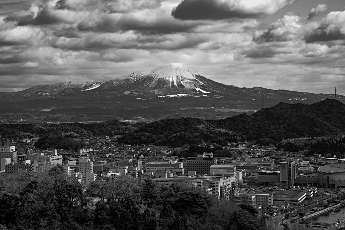 Monochrome photo of Mt. Daisen (Daisen-san) taken from atop the ruins of Yonago Castle, with the city of Yonago below