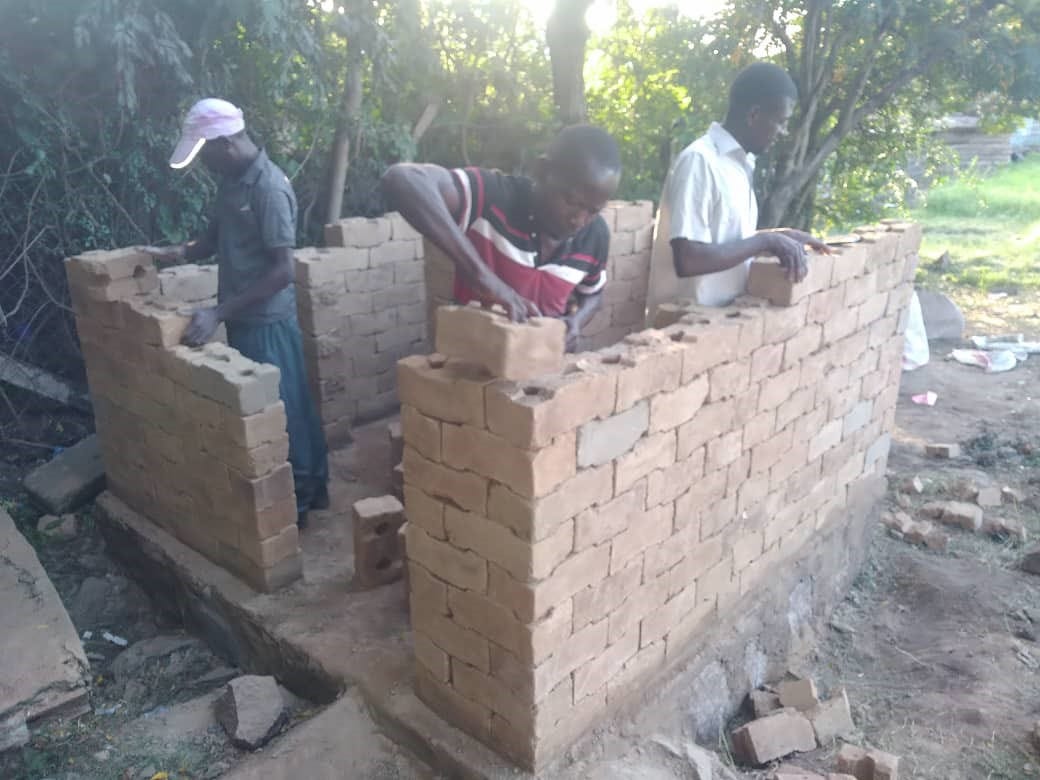 men building a square structure with interlocking bricks 