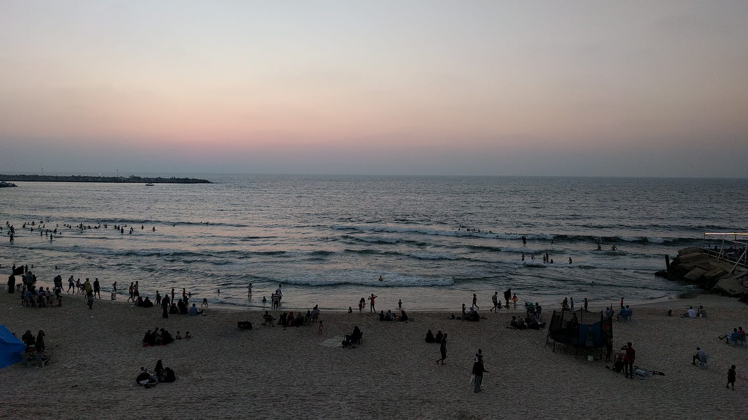 Crowds on an ocean beach at sunset