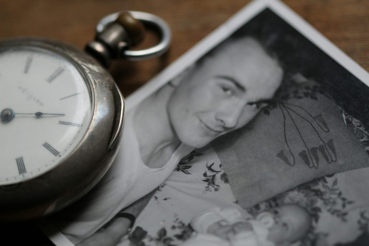 Photo of old black and white snap of adult and baby, alongside a vintage pocket watch