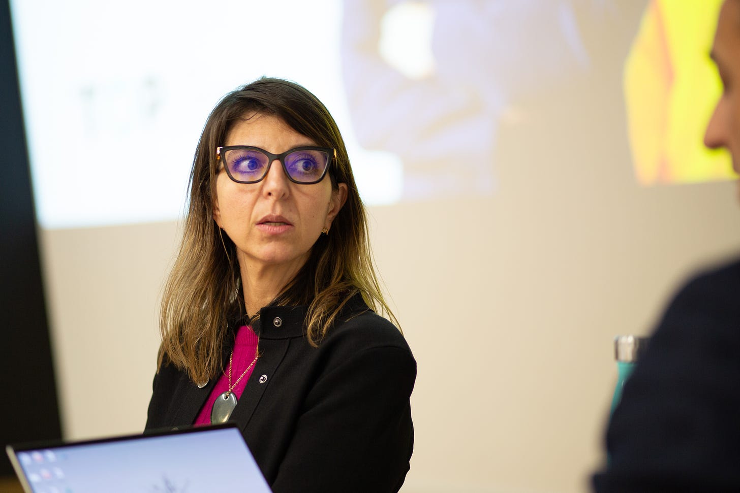 Natalias face looking sideways at an event wearing a glasses and a black jacket