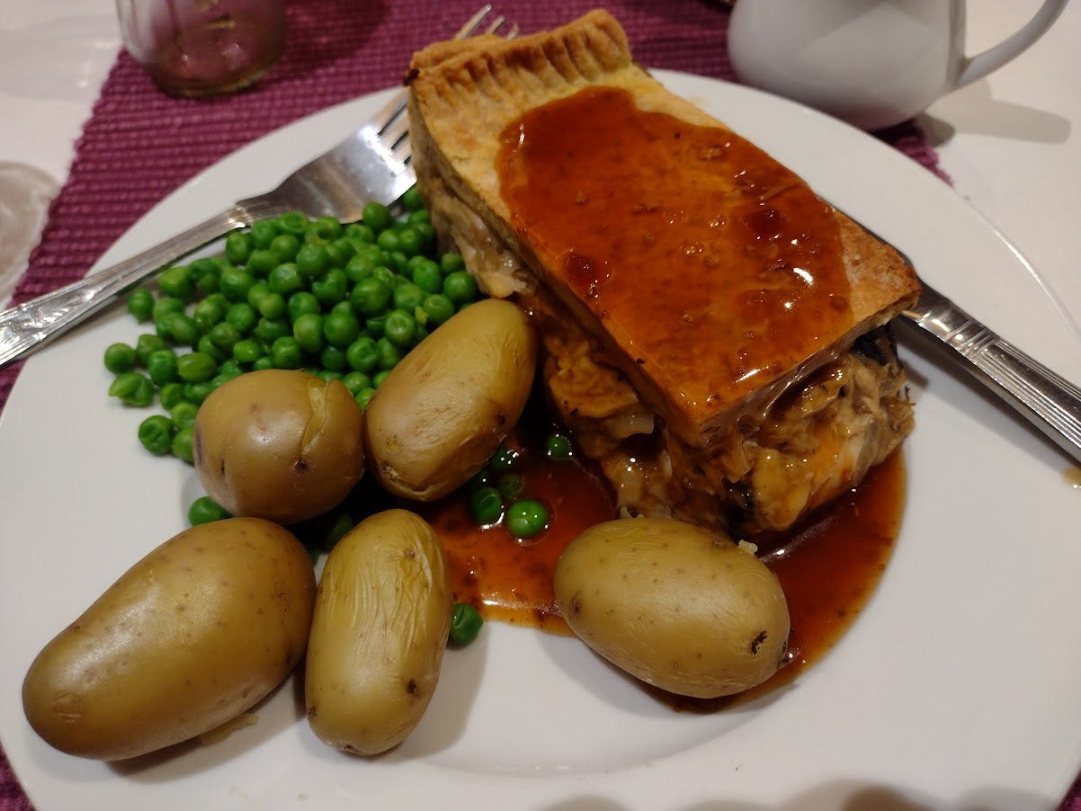 Slice of savory pie with whole small potatoes and peas