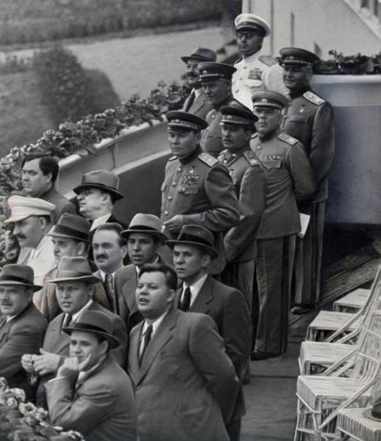 Russian dignitaries, including Stalin, are standing on bleachers watching the Soviet Air Show