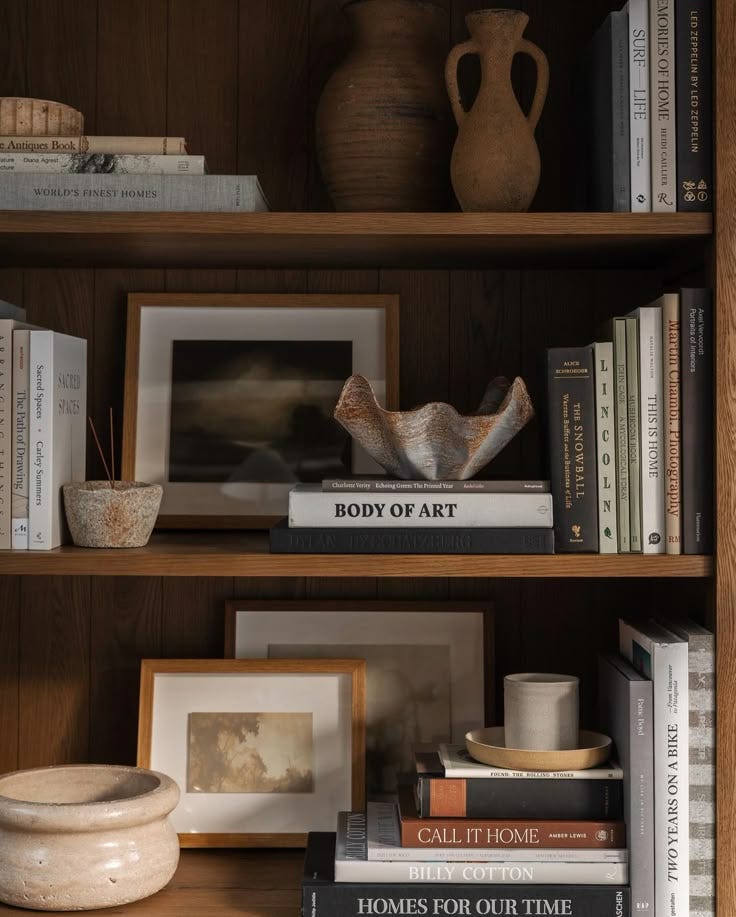This may contain: books, vases and other decorative items on a shelf This may contain: books, vases and other decorative items on a shelf