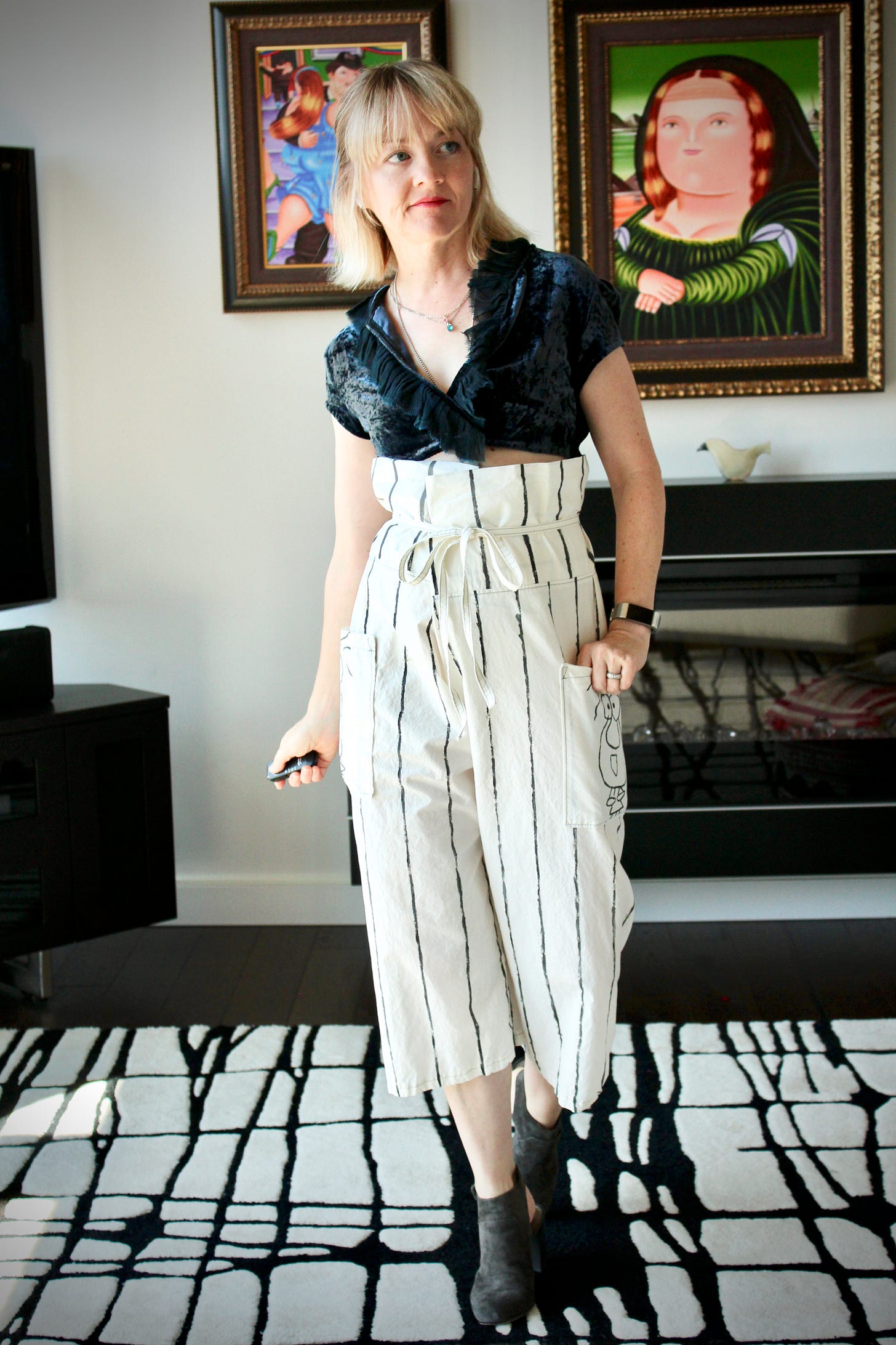 Sherry Dryja of Petite Over 40 models a pair of paper bag waist pants she created from cream colored bedsheets. She has painted the pants with gray pinstripes and cartoon characters designed by her husband on each pocket. She's wearing a cropped velvet jacket made by Tina Witherspoon of BOHO Republic.