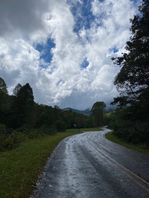 clouds parting to blue sky over windy country road