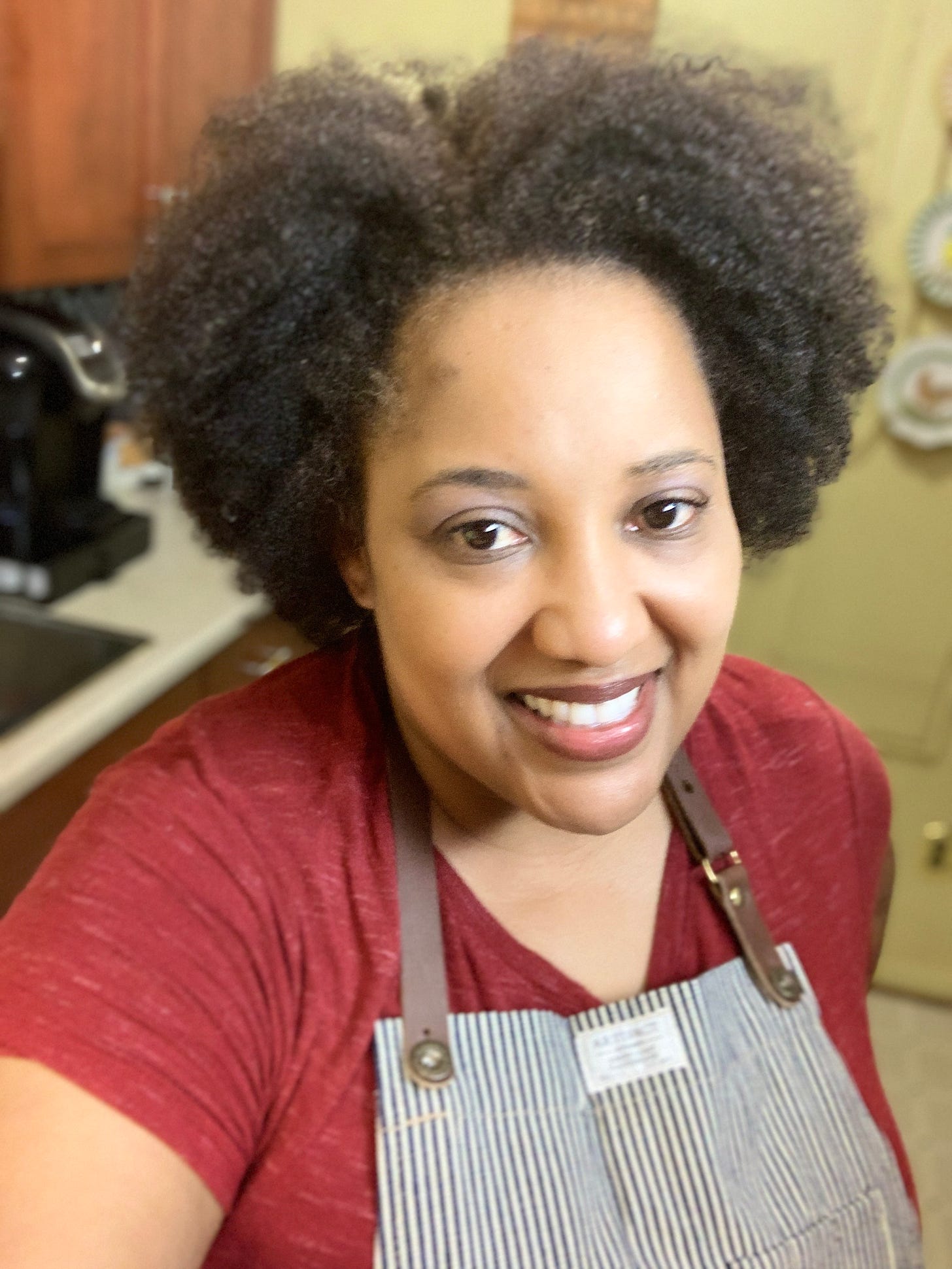 African American woman smiling at the camera wearing an apron in the kitchen