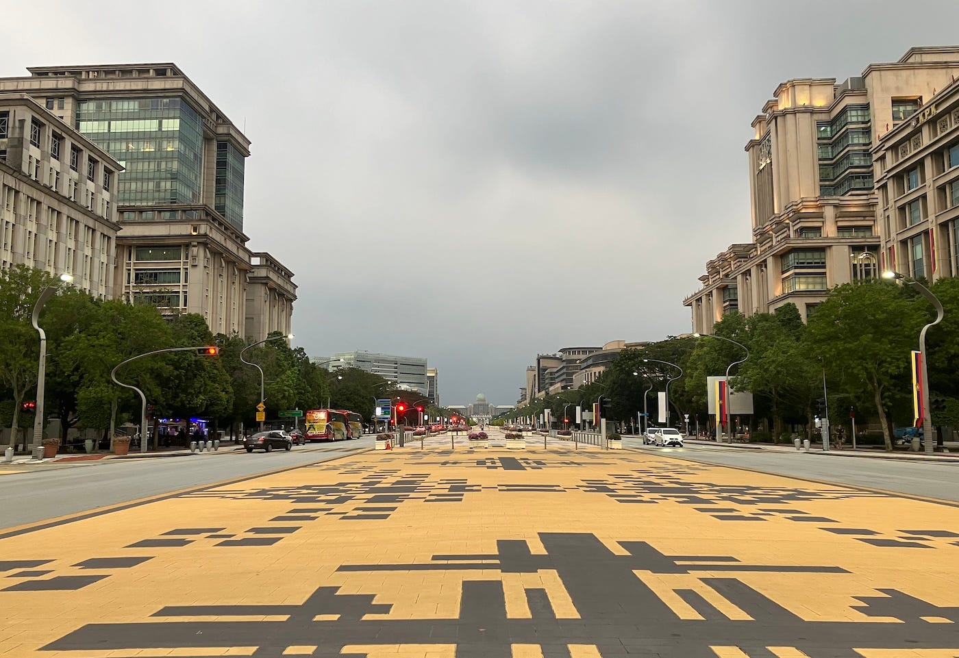 A wide boulevard separates a main road with large buildings on either side