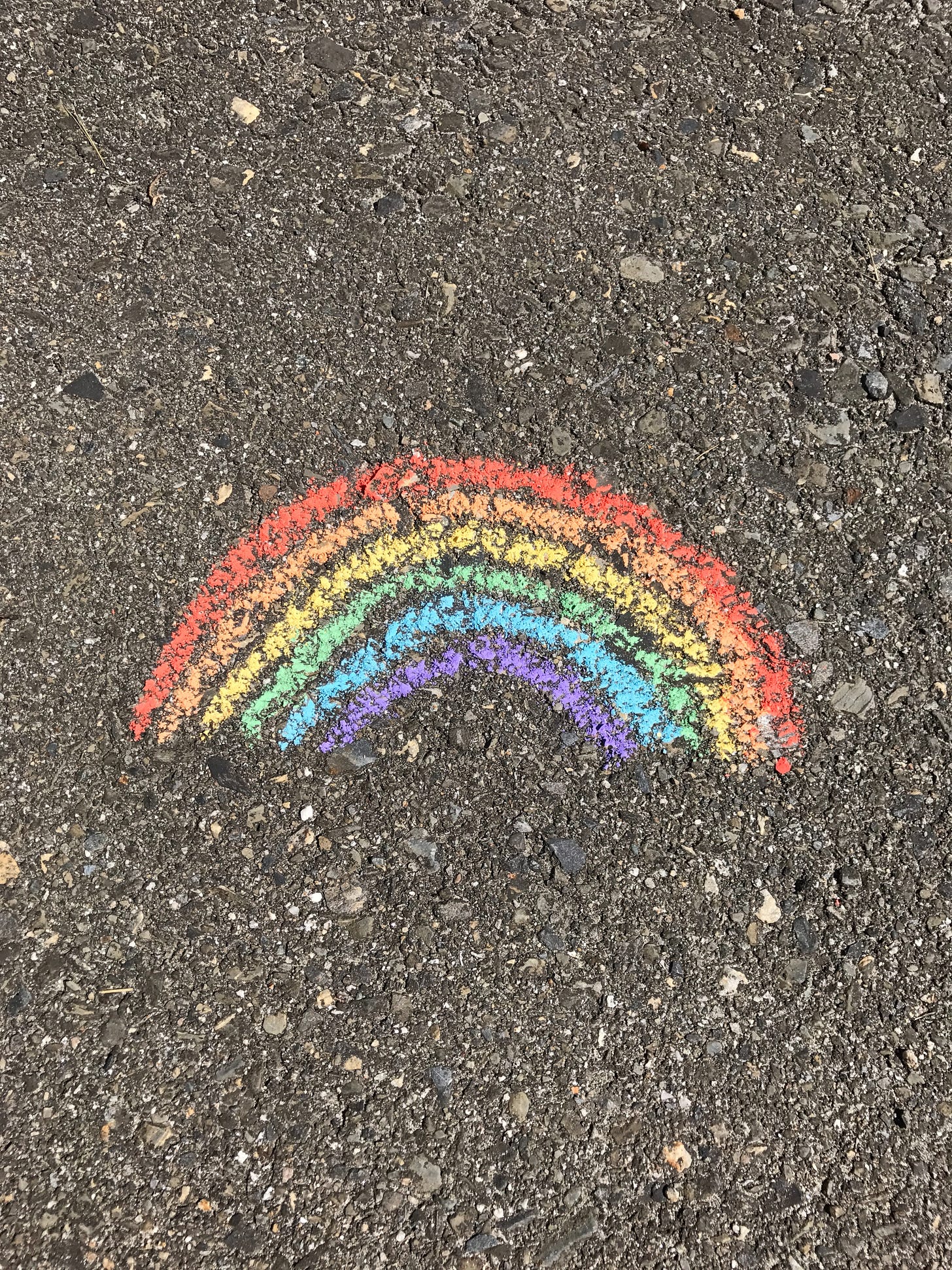 Handchalked rainbow on gravel.