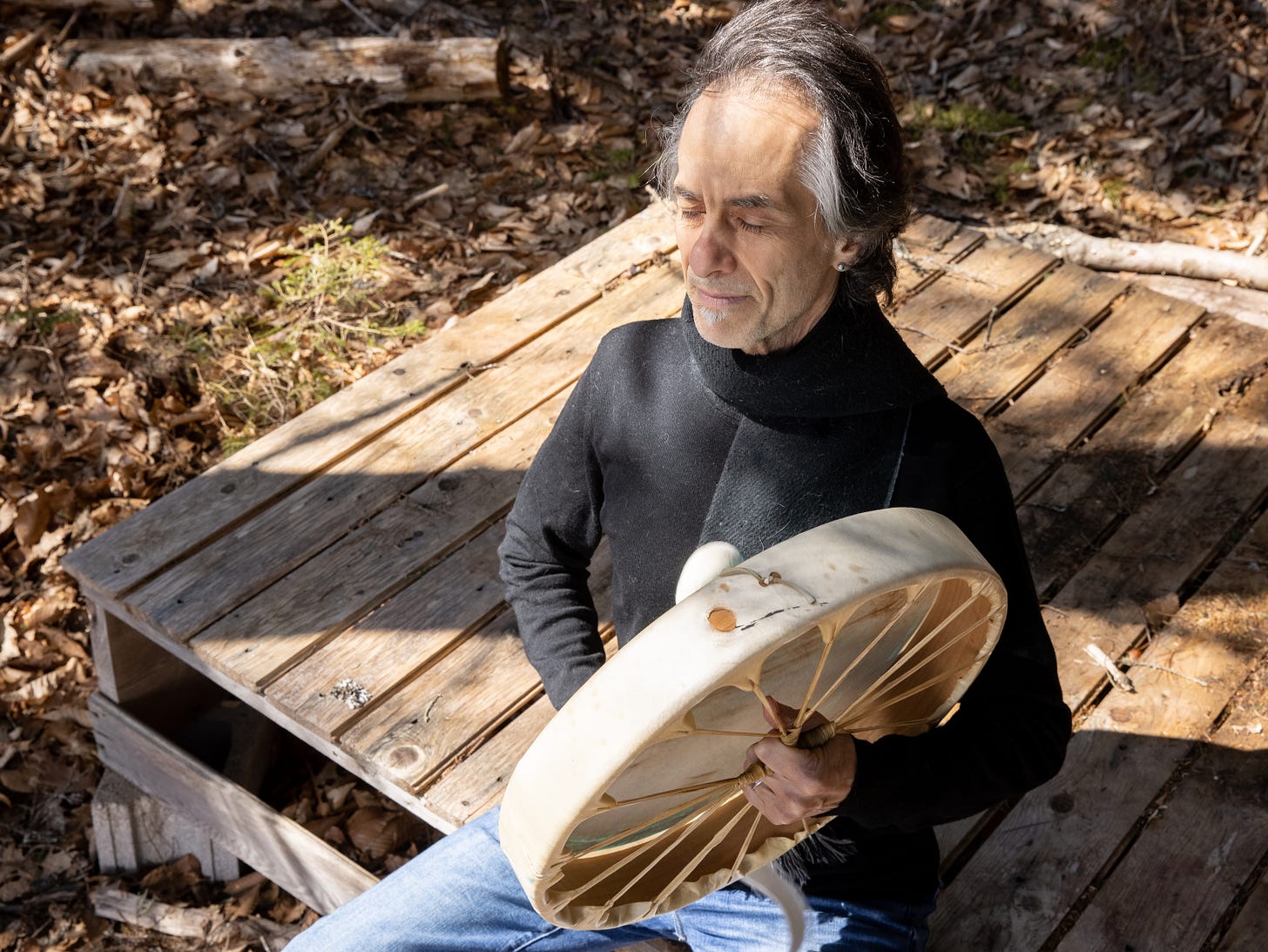 man in woods playing drum shamanism