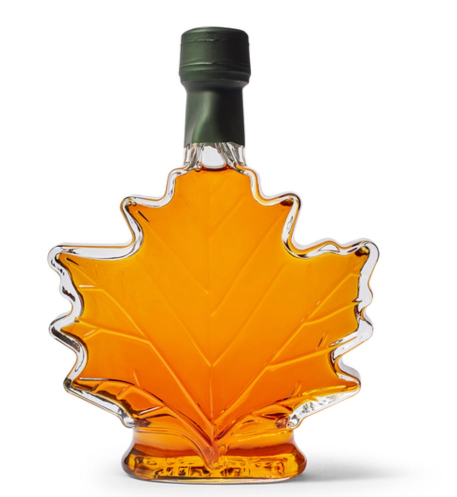 a maple leaf shaped glass jar full of maple syrup