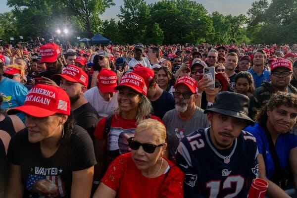 A large group of people, many wearing red Make America Great Again caps.