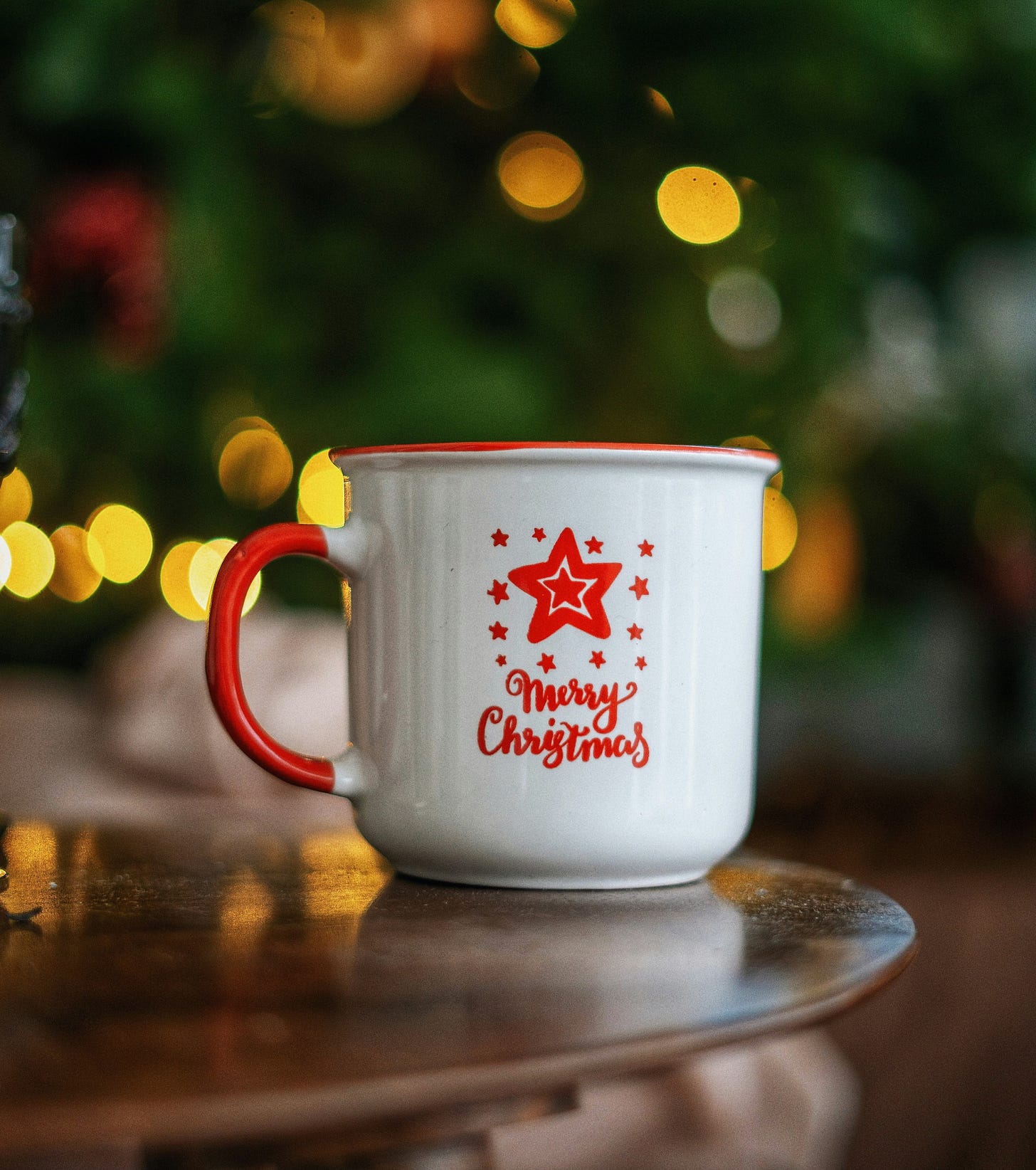 red and white ceramic merry Christmas mug against a Christmas tree backdrop red and white ceramic merry Christmas mug against a Christmas tree backdrop